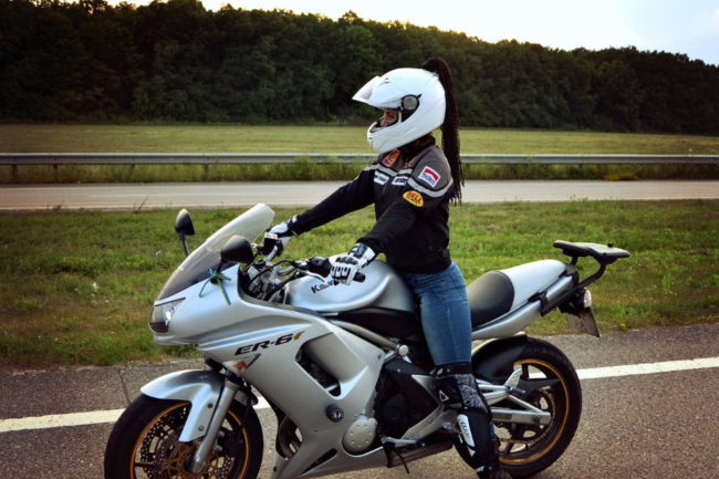Серебристый мотоцикл Kawasaki-ER-6-F с девушкой в белом шлеме