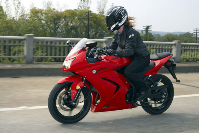 Девушка-байкер на красном мотоцикле модели Kawasaki Ninja 250