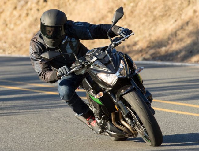 Вид спереди стильного мотоцикла модели Kawasaki Z800 с гонщиком в черном шлеме