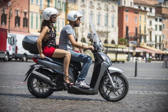 Парень с девушкой в белых шлемах на двухместном скутере
