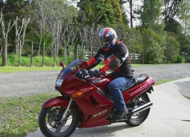 Байкер в джинсах на мотоцикле Kawasaki ZZR 250 малинового окраса