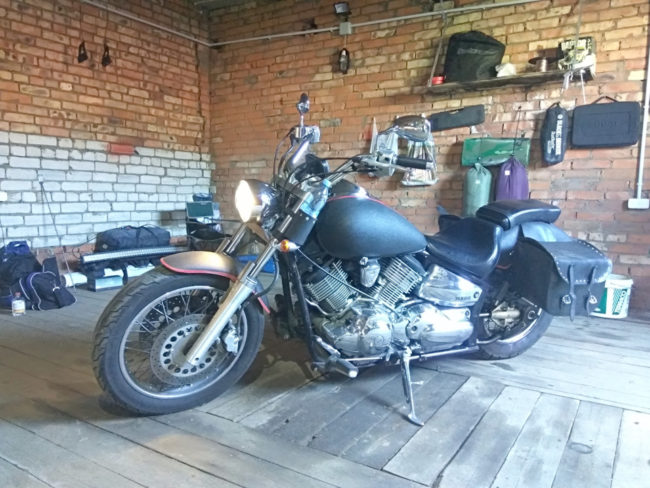 Мотоцикл круизного типа Yamaha 1100 Drag Star в гараже на смотровой яме