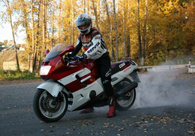 Красно-белый байк японского производства Honda CBR1000F с мотоциклистом в шлеме