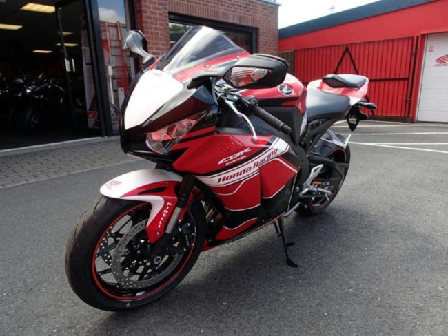 Красно-белый мотоцикл Honda CBR1000RR на подножке с большими зеркалами