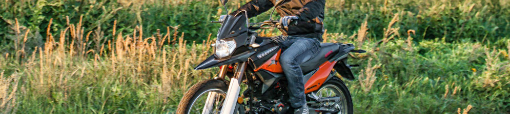 Рослый байкер Irbis XR250R на оранжевом байке в поле