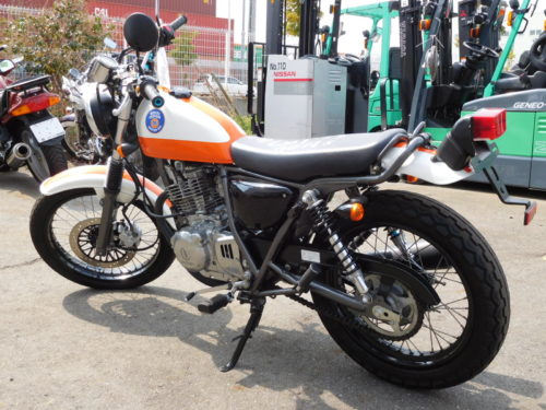 Вид сбоку мотоцикла Suzuki GRASSTRACKER 250 оранжево-белой расцветки