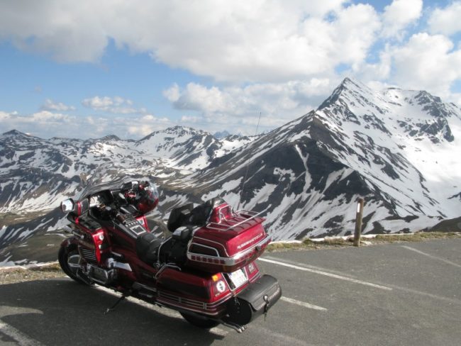 Малиновый мотоцикл Honda GOLD WING GL1500 на фоне заснеженных гор